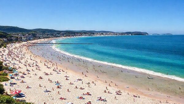 A high definition image of the stunning North Shore District in New Zealand, showcasing its vibrant summer beaches with sun-seekers lounging on Takapuna and Milford beaches. The scene captures the dazzling blue waters of the Hauraki Gulf, surrounded by lush green landscapes and colorful coastal flora. Lively festivals and outdoor events fill the atmosphere with energy, while a gentle coastal breeze adds to the idyllic setting, inviting viewers to immerse in this perfect Kiwi beach experience.