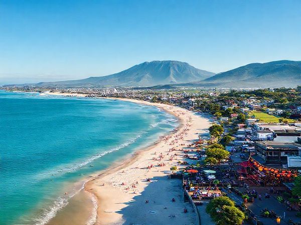 A stunning aerial view of Tauranga, New Zealand, showcasing its vibrant coastline with white sandy beaches, the imposing Mount Maunganui in the background, and lush green vineyards, under a clear blue sky. The scene captures the lively atmosphere of summer with sunbathers on the beach, vibrant cafes spilling onto the streets, and colorful lanterns illuminating a summer festival. Render in high definition for rich detail and clarity.