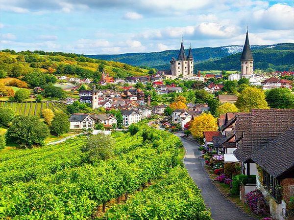 Create a high-definition image of the Romantic Road in Germany, showcasing the picturesque landscape during each season: lush green vineyards and bustling towns in summer, a serene snowy wonderland during winter with charming Christmas markets, vibrant autumn foliage with red and gold leaves in fall, and blooming flowers with lively gardens in spring. Incorporate iconic fairy-tale castles and medieval towns throughout, capturing the enchanting atmosphere of this storybook route.
