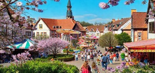 A captivating view of Recklinghausen in spring, showcasing vibrant blossoms and lush greenery, with families enjoying the Osterkirmes festival, amusement rides in the background, and cheerful pastel colors illuminating the streets. The scene captures the essence of renewal and outdoor joy, framed by picturesque historical architecture, all in high definition.