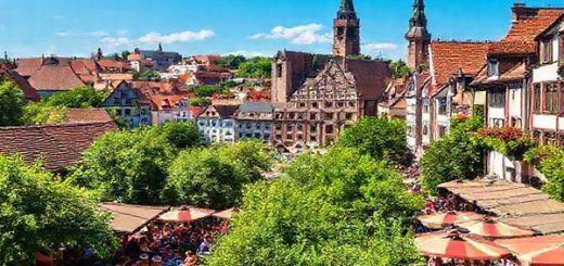 Create a high-definition image of Nürnberg in summer, showcasing vibrant outdoor scenes with lush green parks, lively beer gardens filled with people clinking mugs, and a backdrop of medieval architecture under a clear blue sky. Include colorful street festivals with artists and musicians, capturing the city's energetic atmosphere and the essence of Bavarian culture in full bloom.