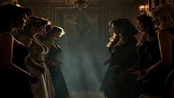 A moody, high-definition image of a stylish, opulent movie set inspired by "Wake Up Dead Man: A Knives Out Mystery (2025)," featuring a diverse group of women characters in 1920s-inspired outfits, engaging in a dramatic dialogue amidst a backdrop of intricate decor and shadows. The atmosphere should convey a sense of mystery and suspense, with sharp lighting highlighting their expressions of empowerment and determination, reflecting both traditional archetypes and a break from them.