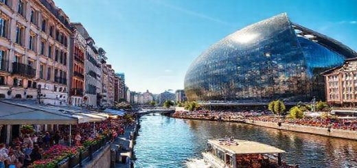 A stunning high definition image of HafenCity in summer, showcasing the vibrant atmosphere with outdoor festivals, bustling streets, and the striking Elbphilharmonie in glass reflected in the sun. Include people enjoying the waterfront cafes, blooming flowers, and a lively boat tour on the Elbe River, all under a clear blue sky.