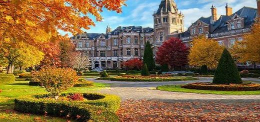 A high definition image of Invercargill, New Zealand, showcasing its stunning Victorian and Edwardian architecture surrounded by the vibrant colors of autumn foliage. Include a serene scene of Queens Park with manicured gardens, and a gentle breeze rustling through fallen leaves, capturing the essence of tranquility in the city during this picturesque season.