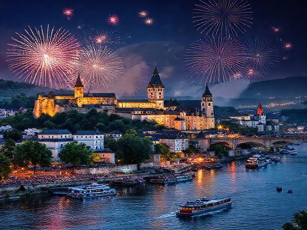 Create a high-definition image of Koblenz during the summer, highlighting the vibrant Rhine in Flames festival. Capture the majestic fortresses set against a backdrop of lush vineyards, with a breathtaking display of fireworks illuminating the night sky. Include lively crowds near the Deutsches Eck, picnicking with views of the confluence of the Rhine and Moselle rivers, and serene boat cruises sailing by historical castles nestled along the riverside. The atmosphere should exude excitement and warmth, showcasing the unique blend of historical charm and natural beauty of this picturesque city.