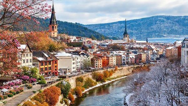 A high definition image depicting the vibrant city of Jena across the four seasons: spring with blooming flowers, summer with lively outdoor festivals, autumn showcasing golden and auburn foliage, and winter blanketed in snow. Include the historic architecture and the winding Saale River, creating a harmonious blend representing Jena's cultural richness and natural beauty.