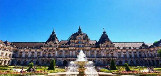 A stunning high-definition image of Zwinger Palace in Dresden, Germany, showcasing its magnificent Baroque architecture surrounded by lush summer gardens in full bloom. Sunlight sparkles on the Fountain Court, with visitors enjoying peaceful strolls among vibrant flowers and greenery. Capture the exquisite details of the palace’s ornate facades under a bright blue sky, while the atmosphere exudes a sense of cultural richness and serenity.