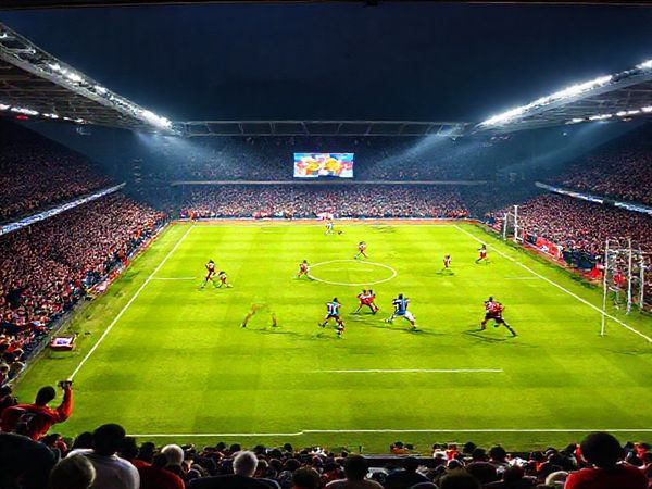 A high-definition image of a tense football match scene at Ashton Gate Stadium, with Bristol City players in vibrant red and Millwall players in bold blue and white jerseys clashing on the pitch. The atmosphere is electric, with passionate fans filling the stands, waving flags and banners. A dramatic backdrop features the dynamic tactics on display, showcasing a tense midfield battle and the iconic stadium illuminated under the December sky. The scoreboard shows the anticipation of a crucial Championship clash, capturing the essence of sport, strategy, and rivalry.