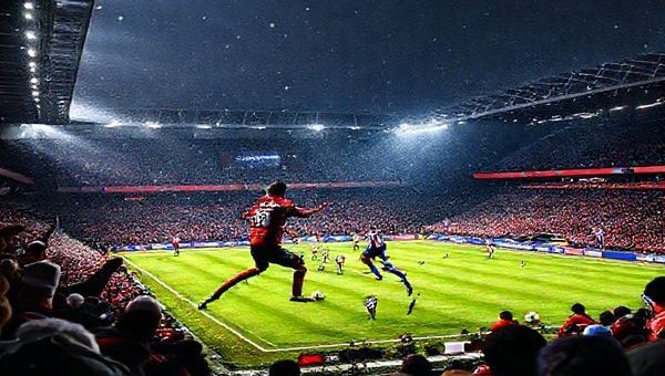 "Create a high-definition image of a dramatic football match scene at Ashton Gate Stadium, depicting the intense rivalry between Bristol City and Leicester City. Capture the chilling winter atmosphere, with fans fervently supporting their teams. Show Bristol City players in dynamic motion, embodying grit and resilience, while Leicester City players display their technical sophistication. Emphasize the contrasting styles of play: swift counters against patient tactical build-ups, and the tense atmosphere as the match unfolds. Highlight vibrant colors, dramatic lighting, and the palpable energy of this Championship clash."