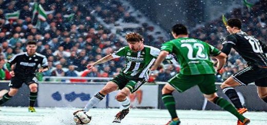 Create a high-definition image of a dramatic soccer match between Breidablik and Shamrock Rovers. Capture the moment where Breidablik's captain, a determined Icelandic player, makes a swift counter-attack on a snowy pitch, with the Shamrock Rovers players positioned defensively in an urban Dublin stadium atmosphere. The crowd is vibrant, immersed in anticipation, with flags waving and a sense of rivalry in the air. Highlight the contrasting styles: Breidablik's gritty resilience against Shamrock Rovers' strategic sophistication, showcasing the intensity and dynamic energy of the Europa Conference League clash.