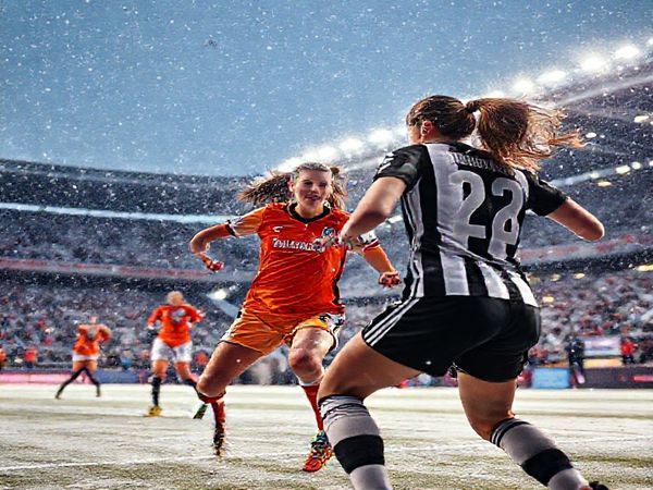 A dramatic scene unfolds in a snow-dusted stadium, where St. Pölten Women and Juventus Women face off in the UEFA Women's Champions League under the twinkling December sky. The players, dressed in their vibrant jerseys, are locked in fierce action, capturing the intensity of the match. St. Pölten's spirited captain Lena Gerhardt orchestrates the midfield, while Juventus's Cristiana Girelli prepares for a powerful strike. The atmosphere is electric, filled with cheers and the cold breath of anticipation. High definition, vivid colors, dynamic movement.