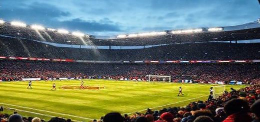 A high-definition scene capturing a thrilling football match between Dundee and Aberdeen at Dens Park on a frosty December evening in 2025. The stadium is illuminated with bright floodlights, showcasing the contrasting styles of the two teams: Dundee's disciplined, gritty players defending resolutely while Aberdeen's colorful, skillful attackers launch an incisive counter-attack. Snowflakes gently fall from the sky as passionate fans cheer in the stands, creating an electrifying atmosphere filled with anticipation and tension.
