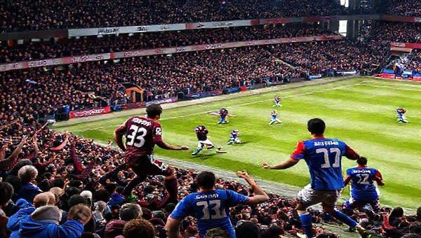 High definition image of a thrilling Premier League match between Burnley and Crystal Palace in December 2025. The stadium is packed with passionate fans, with banners and flags waving. Burnley's players, clad in their deep claret kits, are executing a counter-attack, showcasing their determination and grit. Meanwhile, Crystal Palace players in vibrant blue and red jerseys are displayed in dynamic movement, emphasizing their flair and technical prowess on the ball. Capture the intensity of the game, the clash of styles, and the vibrant atmosphere of football.