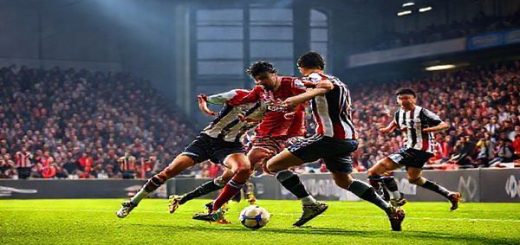High definition image of a dramatic football match between Grimsby Town and Wealdstone, featuring players in vibrant kit colors fiercely contesting the ball in a packed stadium under bright lights. Capture the tension of the midfield battle, showcasing Grimsby’s disciplined defense and Wealdstone’s dynamic play, with passionate fans in the stands adding to the atmosphere. The scene should evoke excitement and anticipation, reflecting the spirit of the FA Cup in December 2025.