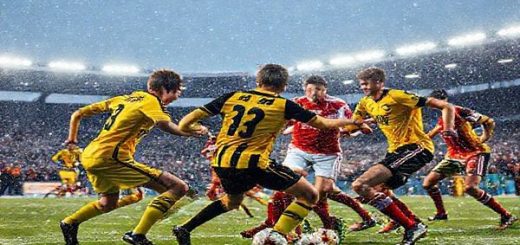 "An intense football match scene under a snowy sky, featuring a dynamic clash between the Young Boys and Lille. The Young Boys, in bright yellow and black jerseys, exhibit high energy and a fast-paced game, while Lille players in red and white uniforms display tactical precision and defensive solidity. The stadium is packed with enthusiastic fans amidst flurries of snow, and the floodlights illuminate the fierce competition. Capture the emotions of determination, excitement, and rivalry in high definition."