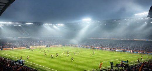 A dramatic scene at Vale Park, December 2025: a high-stakes FA Cup match between Port Vale and Bristol Rovers. The stadium is enveloped in mist, illuminated by floodlights, capturing the tension and excitement of the clash. Port Vale’s underdog spirit is showcased with players in vibrant jerseys, demonstrating defensive solidarity and swift counter-attacks, while Bristol Rovers showcases their fluid, attacking style with dynamic movements and expressive play. The stands are filled with passionate fans, waving flags, in a quintessentially English football atmosphere. High definition.