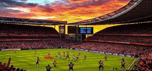 A high-definition image of an intense football match between Port Vale and Bradford City, set against a dramatic sunset. The stadium is packed with cheering fans, wearing the colors of their respective teams. Players clash on the pitch, showcasing a mix of tenacity and skill, with the backdrop of a vibrant sky and the iconic stadium architecture. Capture the energy, emotion, and anticipation of this League One showdown.