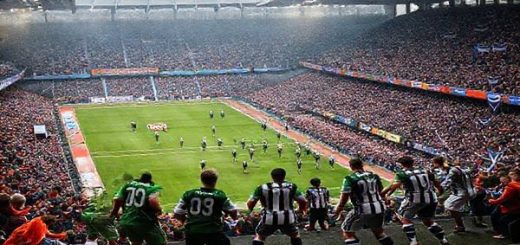 A dramatic Scottish football scene set in December 2025, showcasing a packed stadium during the intense showdown between Greenock Morton and Queen's Park. The image features the two teams in vibrant kits: Morton in deep green, embodying resilience and teamwork, versus Queen's Park in classic black and white, reflecting their rich heritage and attacking flair. Capture the electric atmosphere with fans cheering passionately, colorful banners waving, and a dynamic moment on the pitch, highlighting the clash of Morton's defensive solidity against Queen's Park's fluid style. Make the image in high definition.