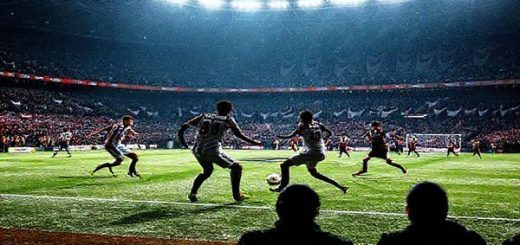A high-definition scene depicting a dramatic football match at the Ricoh Arena under floodlights, showcasing the clash between Midtjylland and Genk. The pitch is glistening with frost, with players like Evander and Mike Tresor in dynamic action, embodying strategic confrontation and fluid gameplay. Tension fills the air as fan banners wave in support, representing the cultures and philosophies of both teams. In the background, the silhouettes of intense coaches strategizing from the sidelines hint at the tactical masterpiece unfolding.