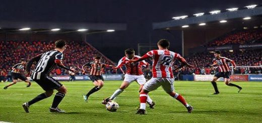 A high-definition image of a tense and dramatic soccer match between Doncaster Rovers and Stockport County on a brisk December evening. The scene captures players in action, showcasing Doncaster's resilient style with a solid defensive line and Stockport's counter-attacking agility. The vibrant stadium is alive with passionate fans, illuminated by floodlights, as the players clash on the field, highlighting the intense tactical battle and emotions of this League One encounter.