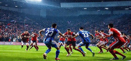 Two football teams clashing on an electrifying evening in December 2025, set in a bustling stadium filled with roaring fans. The scene captures a dramatic moment: Oldham players in vibrant blue jerseys charge down the pitch, while Walsall players in striking red jerseys prepare to defend. Bright stadium lights illuminate the action, with colorful flags waving in the stands, and a snowy backdrop hinting at winter's chill. High definition.