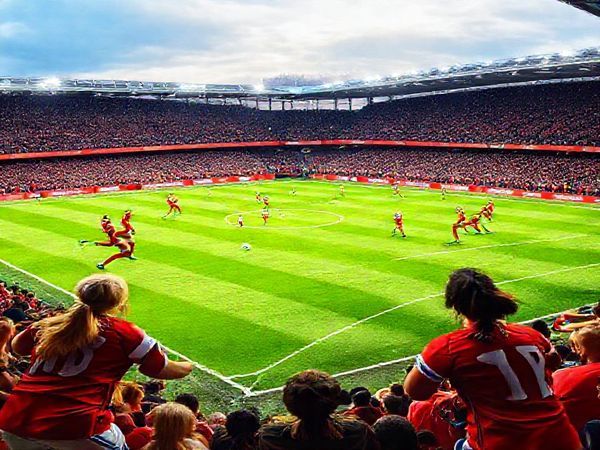 A high-definition image of a vibrant and dynamic women's football match between Arsenal Women and Liverpool FC Women at Meadow Park, December 6, 2025. Capture the intensity of the players on the field, showcasing Arsenal in their iconic red kits displaying fluid attacking play, contrasted with Liverpool in their striking red jerseys showcasing a strong defensive line. The background should feature a lively crowd, filled with eager fans, under a bright winter sky, emphasizing the anticipation and excitement of this highly-anticipated Women's Super League showdown.