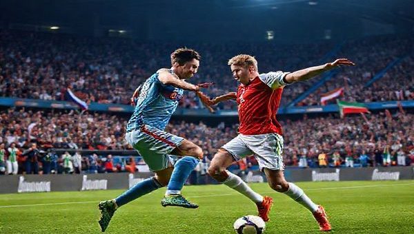 A high-definition image depicting an intense football scene in a stadium filled with passionate fans. In the foreground, a duel between two players symbolizes the clash of styles: Slovakia's Marek Hamsik showcasing finesse and tactical discipline against Northern Ireland's Steven Davis embodying determination and tenacity. The atmosphere is electric, with flags waving and the grass glistening under stadium lights, capturing the high stakes of their World Cup qualifier match.