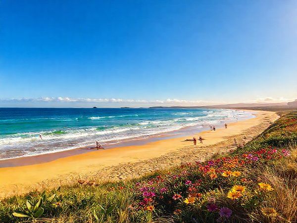 A picturesque coastal scene of Ōpōtiki in summer, featuring golden sandy beaches and the deep blue Pacific Ocean under a clear blue sky. Capture thriving watersports like surfing and kayaking, with vibrant energy all around. Brightly colored flowers bloom along scenic trails in the background, while sunset colors paint the horizon. Include smiling locals enjoying the beach atmosphere. Make the image in high definition.