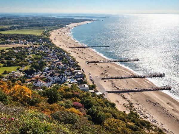 A breathtaking view of Usedom Island showcasing its diverse seasonal beauty: in summer, vibrant beachgoers enjoying sunny shores; in autumn, golden foliage along scenic trails; in winter, serene snow-covered landscapes; and in spring, blooming flowers amid lush greenery. The historic seaside resorts with distinct architecture and long piers should be visible, set against the backdrop of the sparkling Baltic Sea. Capture this charm in high definition.