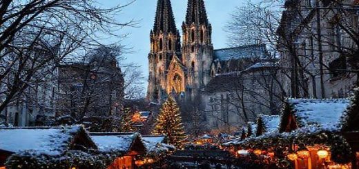 A high-definition image depicting the picturesque city of Köln, Germany, showcasing its iconic Gothic architecture, particularly the Cologne Cathedral, against the backdrop of the festive Christmas market in winter with twinkling lights and glowing trees. The scene should include stalls with warm glows, visitors sipping mulled wine, and the Rhine River softly reflecting the city's charm under the evening sky.