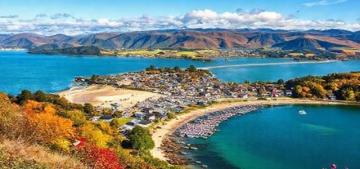 "Create a high definition image of Wairoa, New Zealand, showcasing the lush landscapes and vibrant seasons. Illustrate the stunning Mahia Peninsula during hot summer days with beachgoers enjoying the sun, and incorporate colorful fall foliage around Lake Waikaremoana. Capture the serene winter beauty with cozy scenes of locals dining, contrasted with the blooming spring flowers that hint at new beginnings. Emphasize the blend of culture and nature, with Maori influences and outdoor activities interwoven throughout the scene."