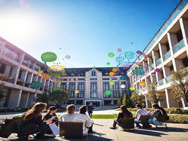 A high-definition image of the Corvinus University of Budapest, featuring a modern architectural design with students engaging in discussion about business ethics outdoors. Surrounding them are symbolic representations of various disciplines such as spirituality, sustainability, and social sciences, depicted as colorful, intertwining elements that create a vibrant tapestry, reflecting the interdisciplinary approach of the Business Ethics Center. The scene is set under a bright blue sky, portraying a hopeful future for business ethics education.