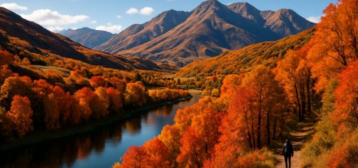 A breathtaking high-definition landscape of Southland District during autumn, showcasing rolling hills adorned with vibrant hues of orange, gold, and deep red foliage. In the foreground, a serene winding river reflects the colorful trees, while distant, rugged mountains rise majestically under a clear blue sky. A few scattered clouds add depth to the scene, and a lone figure is seen walking a forested trail, embodying the peaceful exploration of this stunning wilderness.